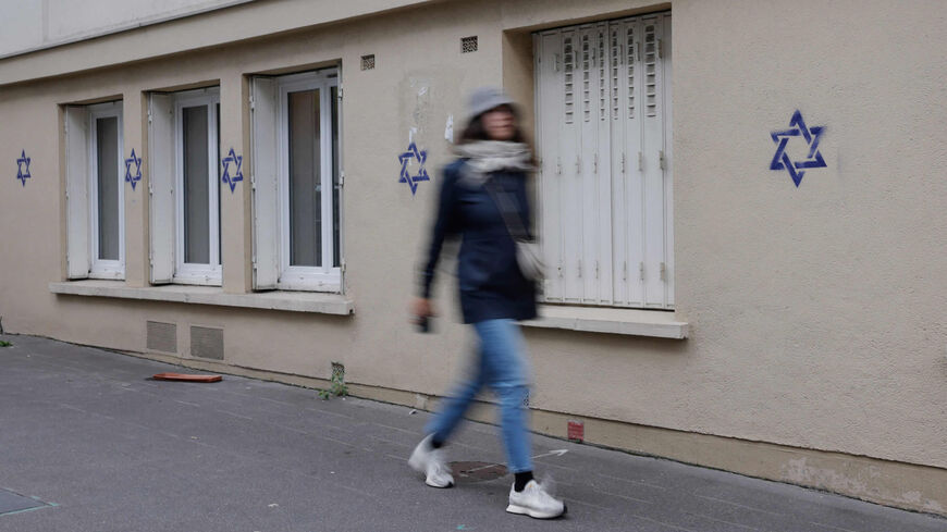 A woman walks along a building whose facade is covered with Stars of David painted during the night, in the Alesia district of Paris, France, Oct. 31, 2023.