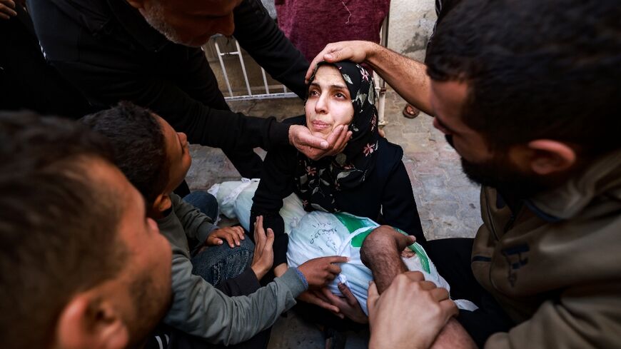 People try to comfort a woman holding the body of her baby girl killed in a strike on Rafah