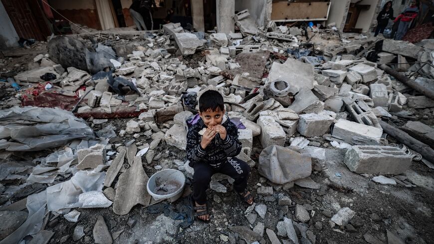 A child eats amid the rubble of destroyed buildings following Israeli bombardment in Rafah in the southern Gaza Strip