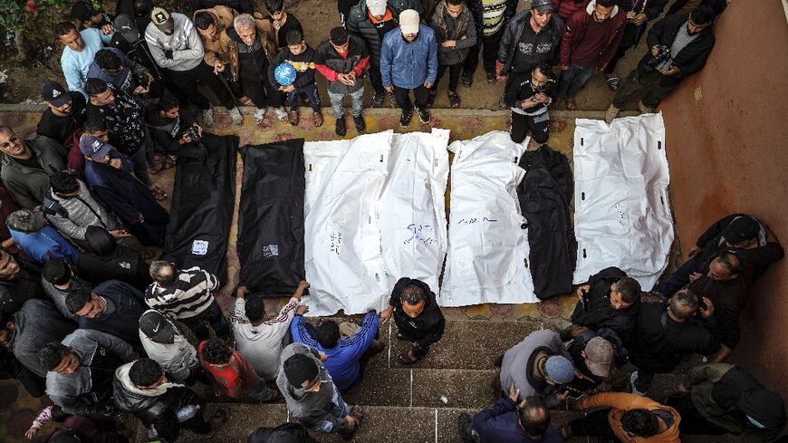 People stand over the shrouded bodies of loved ones killed during Israeli bombardment, at Nasser hospital in Khan Yunis