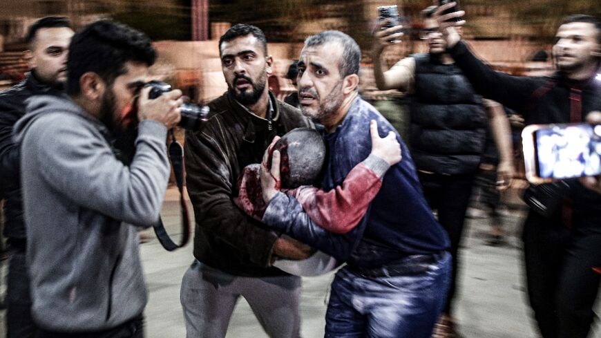 A man carrying a child, wounded in an Israeli bombardment, arrives to Nasser hospital in Khan Yunis in the southern Gaza Strip on December 17, 2023