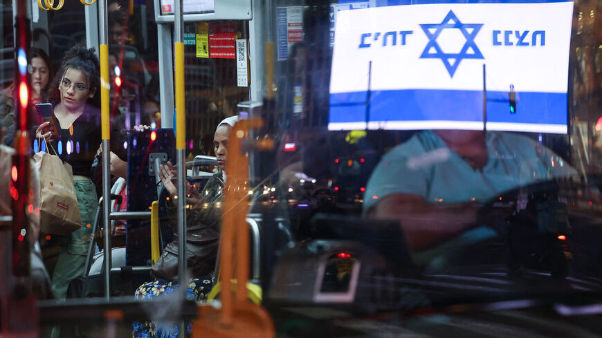 An Israeli flag reading "together we win" is reflected in a bus passing in front of a demonstration held by Israeli left-wing activists near the Ministry of Defence in Tel Aviv on December 5, 2023, calling for a ceasefire and exchange of hostages amid ongoing battles between Israel and Hamas. (Photo by AHMAD GHARABLI / AFP) (Photo by AHMAD GHARABLI/AFP via Getty Images)