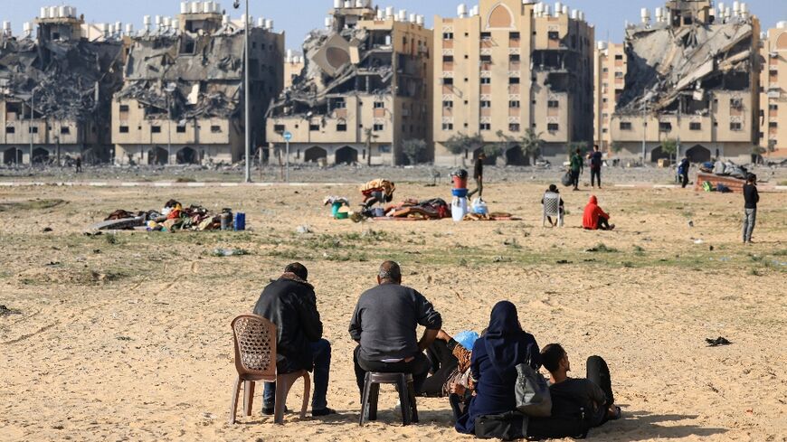 Residents of the Qatari-funded Hamad City residential complex in the Gaza Strip sit outside after  Israeli air strikes hit the development