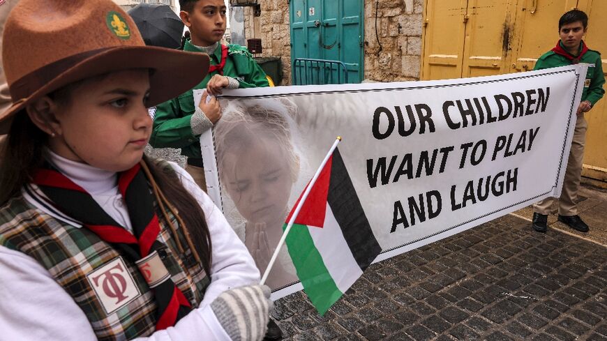 Palestinian youth members of the scouting movement hold up banners calling for an end of the conflict in the Gaza Strip