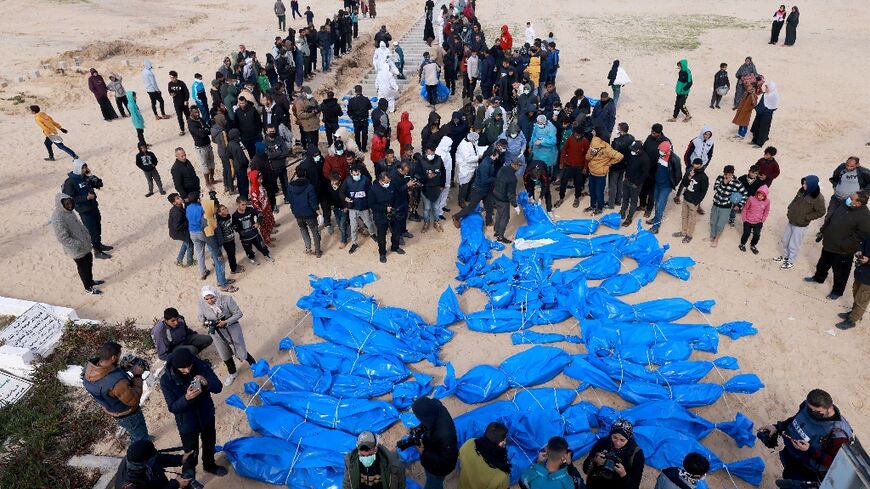 Palestinian health ministry staff prepare to bury dozens of unidentified Gazans in a mass grave after their bodies were exhumed then returned by Israel, according to Gaza officials