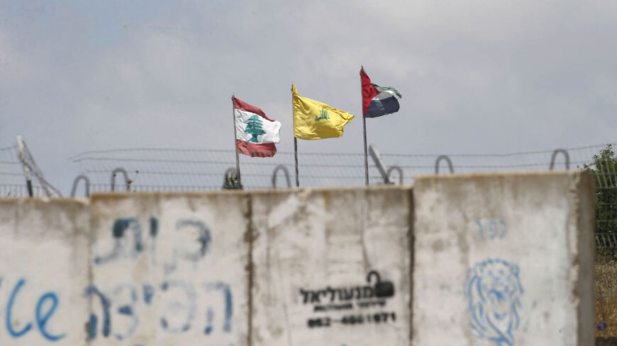 A picture taken on July 3, 2022 from the Israeli Kibutz of Baram, shows the flags of (L to R) Lebanon, Hezbollah and Palestine swaying in the wind on the Lebanese side of the border with Israel.