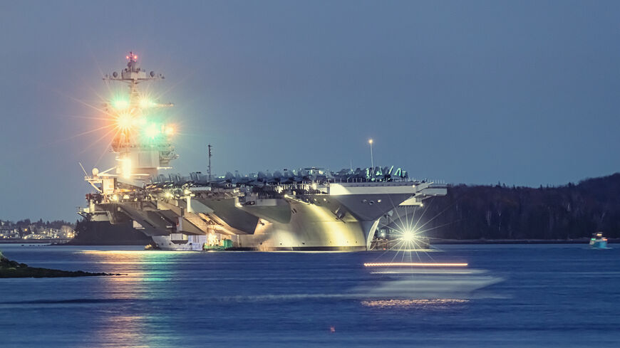 American aircraft carrier anchored in a harbor after offshore training exercises.