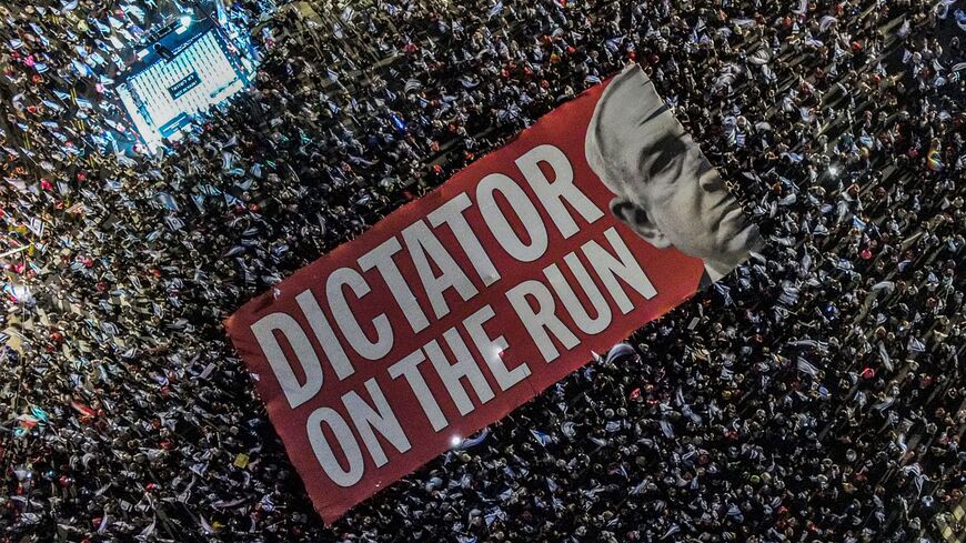 TOPSHOT - This aerial view shows demonstrators unfurling a giant banner against Israeli Prime Minister Benjamin Netanyahu during a rally against the Israeli government's judicial overhaul plan near Azrieli Mall in Tel Aviv on September 23, 2023. (Photo by Jack GUEZ / AFP) (Photo by JACK GUEZ/AFP via Getty Images)