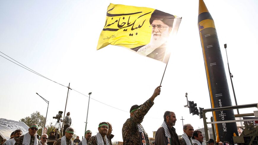 Members of Iranian paramilitary's Basij forces march next to the fourth generation Khorramshahr ballistic missile Khaibar displayed during an anti-Israeli rally to show their solidarity with Palestinians, in Tehran on November 24, 2023. (Photo by AFP) (Photo by STR/AFP via Getty Images)