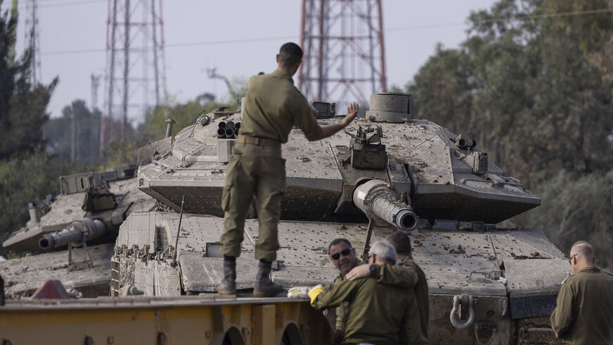 SOUTHERN ISRAEL - JANUARY 02: An Israeli soldier directs a tank to be loaded on a truck on January 02, 2024 in Southern Israel, near the border to Gaza. Prior to annnouncing the withdrawal of some troops from Gaza, Israel extended its ground offensive into densely populated neighborhoods in the central part of the territory, forcing a fresh wave of displacement to south. Meanwhile, its aerial campaign continued apace across the territory as it seeks to destroy Hamas following the militant group's Oct. 7 att