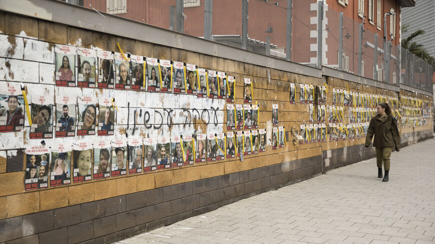 TEL AVIV, ISRAEL - JANUARY 30: An Israeli soldier passes by a wall with photos of hostages held by Hamas in the Gaza Strip on January 30, 2024 in Tel Aviv, Israel. The Israeli prime minister's office referred to as "constructive" the recent high-level talks on a proposed pause in fighting in Gaza, as well the release of Israeli hostages held there. The potential deal, which is being brokered by Qatar and Egypt, would also entail the release of Palestinian prisoners held in Israel and other conditions. (Phot