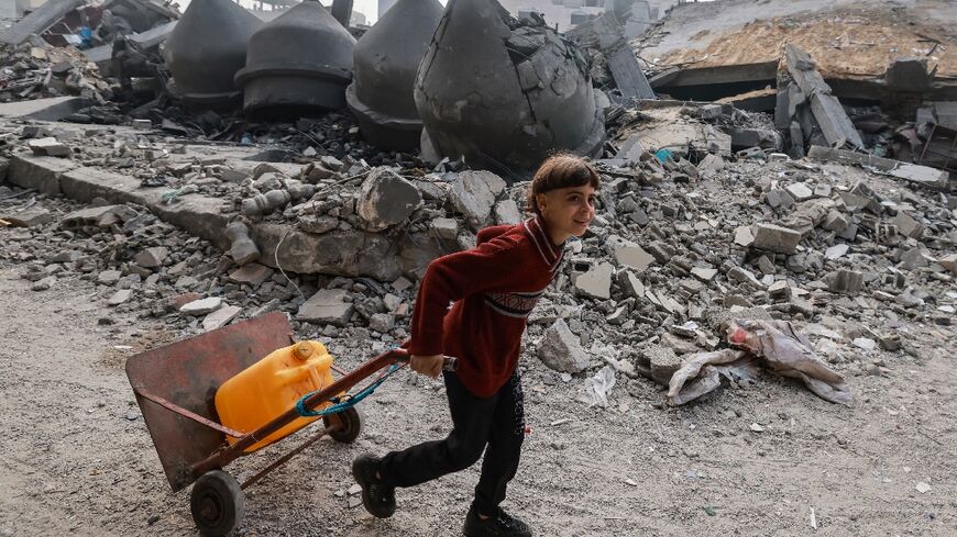 A child pulls a trolley with a water container past the Al-Faruq mosque, levelled by Israeli bombardment in Rafah in the southern Gaza Strip