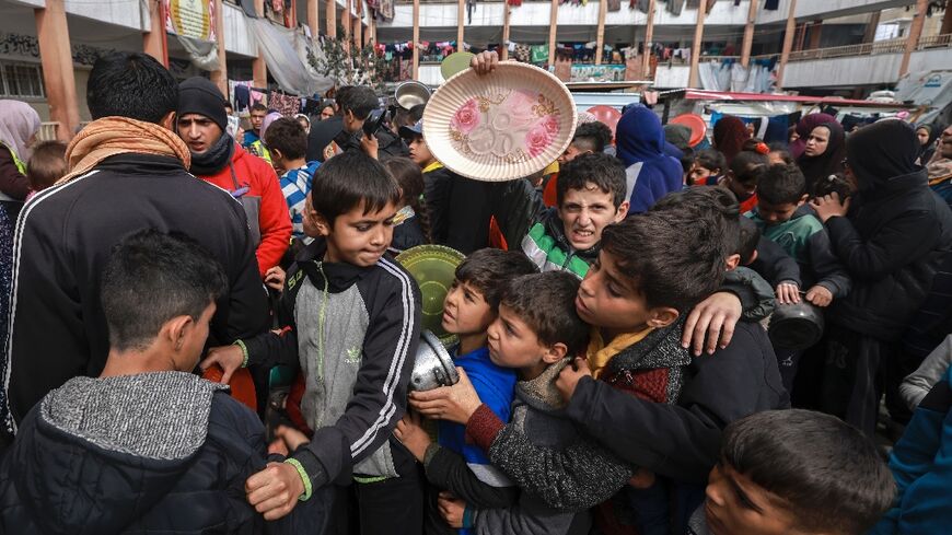 Displaced Palestinian children gather to receive food at a government school in Rafah in the southern Gaza Strip