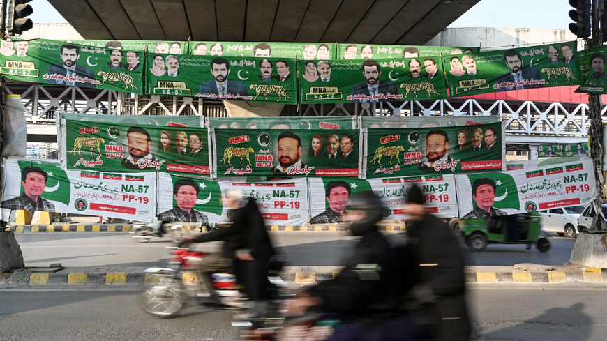 Commuters ride past banners of Pakistan's political parties displayed along a street in Rawalpindi on January 15, 2024 ahead of the country's upcoming general election. Three-time Prime Minister Nawaz Sharif's Pakistan Muslim League (Nawaz) party, the frontrunner for country's delayed elections began campaigning on January 15, after a weekend court decision effectively sealed the opposition party of former Prime Minister Imran Khan out of the race. (Photo by Aamir QURESHI / AFP) (Photo by AAMIR QURESHI/AFP 