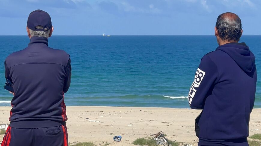 Palestinian men watch the Open Arms charity vessel bringing the first shipment of food aid to Gaza via a new maritime corridor from Cyprus