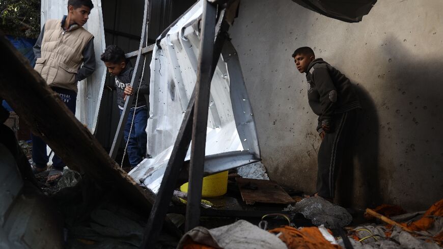 Children check the damage at a bombarded makeshift shelter near the Emirati hospital in Rafah