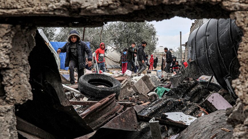 Displaced Palestinians inspect the damage to their tents following overnight Israeli bombardment in Rafah 