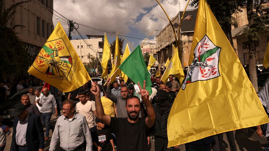 A man raises the Hamas flag as other wave the Fatah emblem during a demonstration in the occupied West Bank city of Hebron to show solidary with the Palestinians of the Gaza Strip on Oct. 20, 2023.