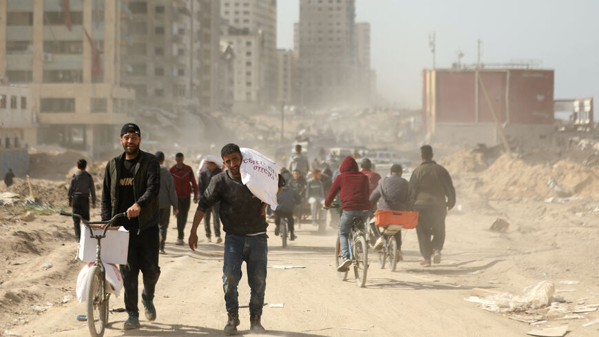 Palestinians transport bags of flour as humanitarian aid arrives in Gaza City on March 6, 2024, amid the ongoing conflict between Israel and the Hamas militant group.