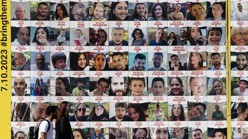 People pass by a building covered with photos of hostages who have been released or are still being held in the Gaza Strip, on March 26, 2024 in Tel Aviv, Israel.