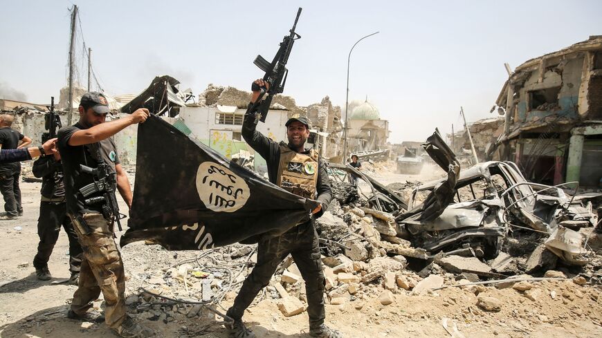 Members of the Iraqi Counter-Terrorism Service (CTS) cheer as they carry upside-down a black flag of the Islamic State (ISIS) group in the Old City of Mosul on July 2, 2017.