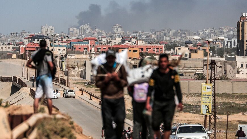 People flee as smoke rises above buildings near the Al-Shifa hospital compound during an Israeli bombardment in Gaza City