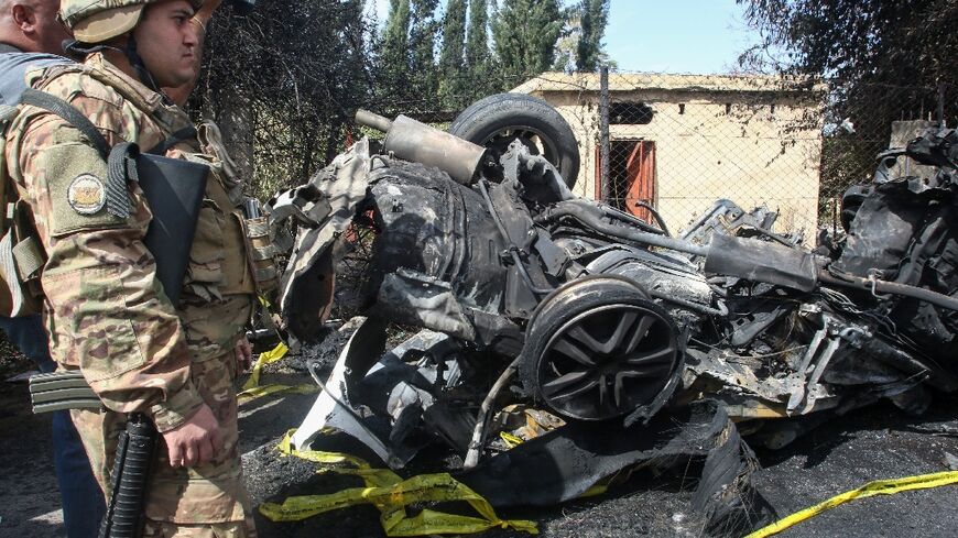 A Lebanese soldier surveys the mangled wreck of a car after what state media says was an Israeli strike killed its driver, a Hamas militant, as well as a passer-by