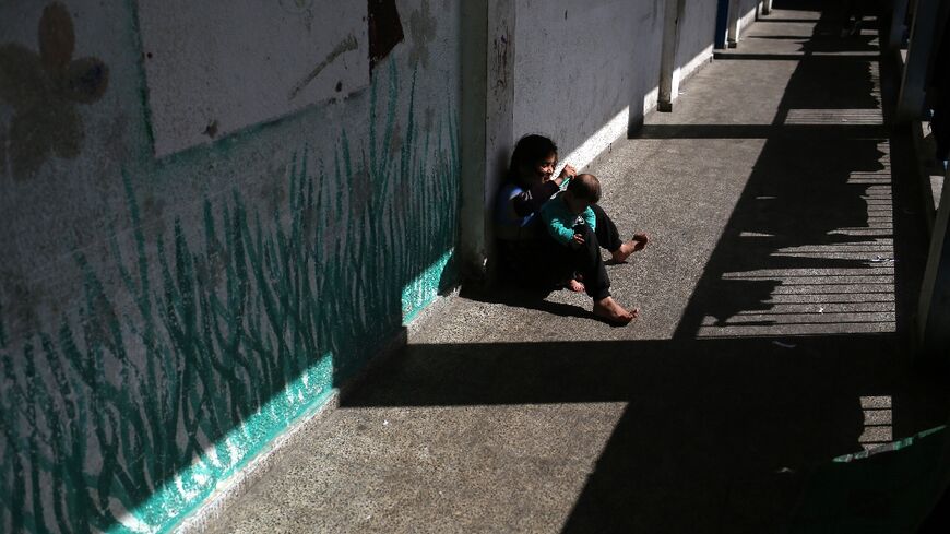 A girl brushes the hair of her sibling at a Gaza school now housing displaced families 