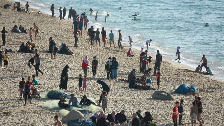 Children paddled in the sea and their friends played ball games on the sand  -- but Gaza's war was never far away