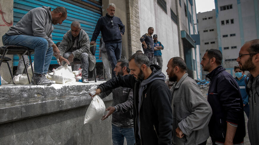 A man hands out bags of flour during the distribution of humanitarian aid in Gaza City on March 17, 2024, amid ongoing battles between Israel and the militant group Hamas.