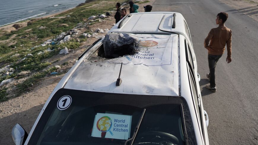 People gather around the carcass of a car used by US-based aid group World Central Kitchen.