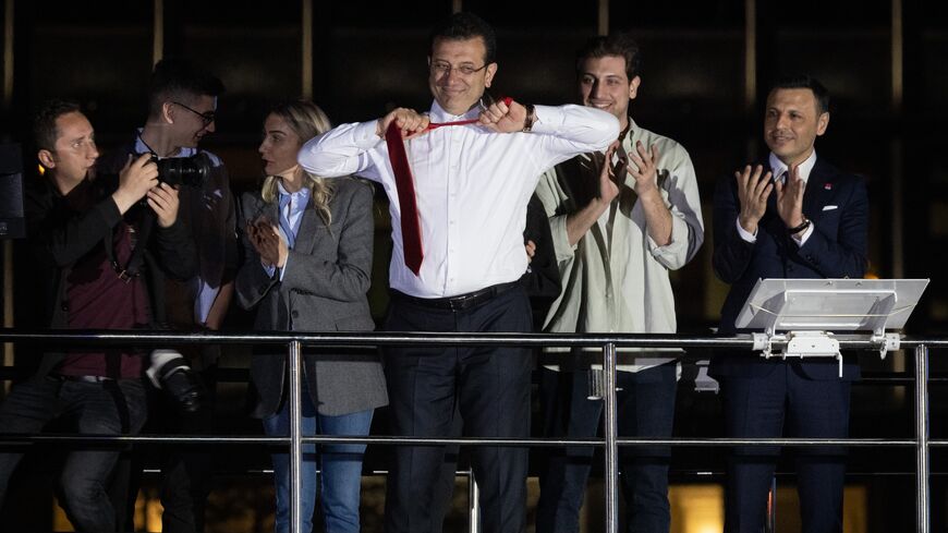 Ekrem Imamoglu, Istanbul mayor and the Republican People's Party (CHP) candidate, takes off his tie from atop a campaign bus while claiming victory surrounded by family members on April 1, 2024 in Istanbul, Turkey.