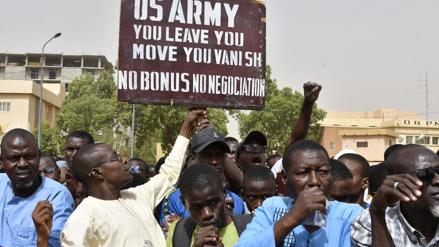 Protesters react as a man holds up a sign demanding that soldiers from the United States Army leave Niger without negotiation during a demonstration in Niamey, on April 13, 2024. Thousands of people demonstrated on April 13, 2024 in Niger's capital Niamey to demand the immediate departure of American soldiers based in northern Niger, after the military regime said it was withdrawing from a 2012 cooperation deal with Washington. (Photo by AFP) (Photo by -/AFP via Getty Images)