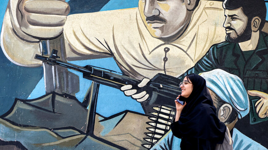 A woman walks past an anti-Israeli mural depicting fighters with assault rifles along a wall in Palestine Square in Tehran on April 14, 2024. Iran on April 14 urged Israel not to retaliate militarily to an unprecedented attack overnight, which Tehran presented as a justified response to a deadly strike on its consulate building in Damascus. (Photo by ATTA KENARE / AFP) (Photo by ATTA KENARE/AFP via Getty Images)