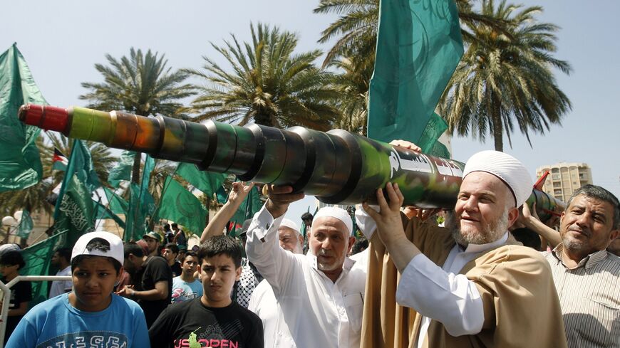 A man holds a mock Qassam rocket during a rally organised by Lebanese and Palestinian supporters of the Islamist movement Hamas and the Islamic Group, Jamaa Islamiya in solidarity with Palestinians in the Gaza strip where Hamas is engaged in a major confrontation with the Israeli army on July 11, 2014 in the southern Lebanese city of Sidon. Two Palestinians were killed in an Israeli strike, raising the toll in four days of violence to 100, Gaza health ministry spokesman Ashraf al-Qudra said. AFP PHOTO / MAH