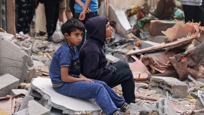 Palestinian boys sit on building rubble following overnight Israeli bombardment in Rafah in the southern Gaza Strip