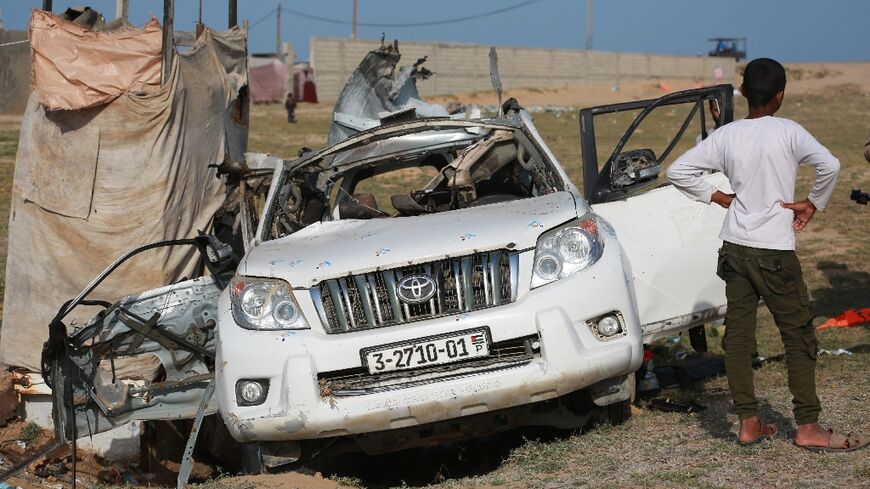 People gather around a car used by US-based aid group World Central Kitchen that was hit by a strike in Deir al-Balah in the central Gaza Strip