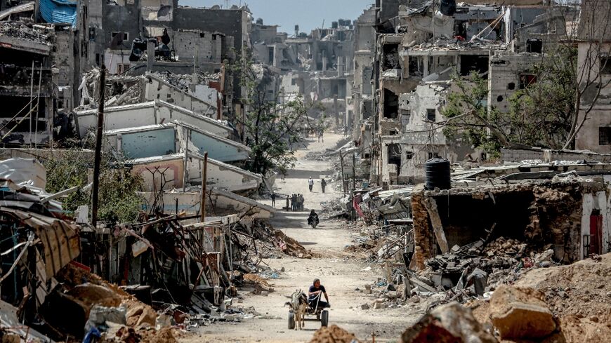 Palestinians walk on a road lined with destroyed buildings in Khan Yunis, where intense fighting raged in February 2024