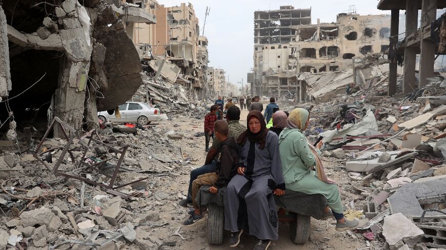 A Palestinian family rides on a donkey-drawn carriage between damaged buildings in Khan Yunis on April 8, 2024 after Israel pulled its ground forces out of the southern Gaza Strip