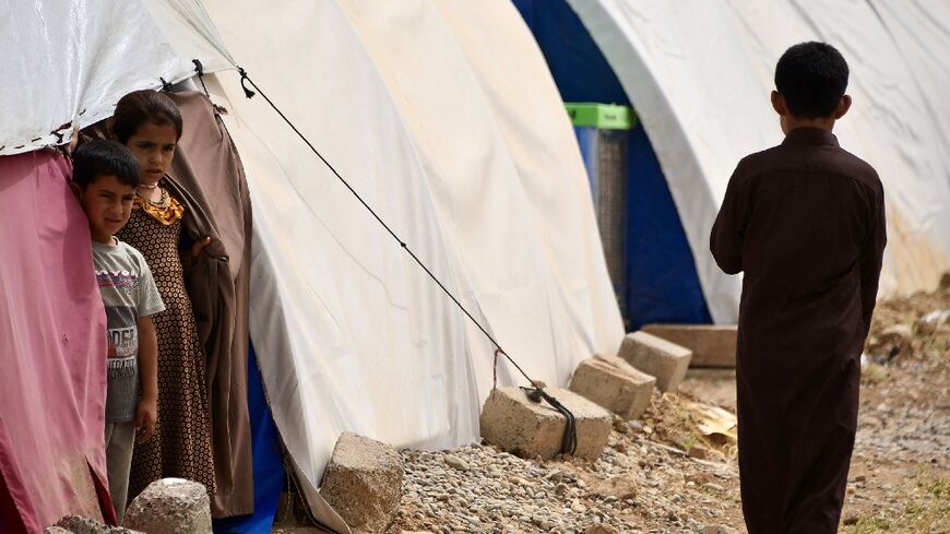 Children stand by tents in April 2024 at the Al-Jadaa camp south of Mosul which houses Iraqi families who have been repatriated from Syria's Al-Hol camp