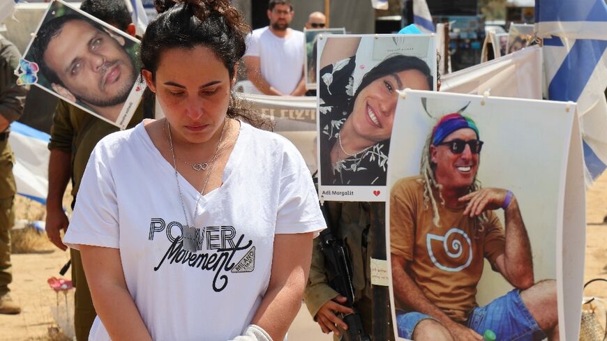 Israeli mourners observe two minutes of silence on Memorial Day, among portraits of hostages held by Hamas militants in Gaza