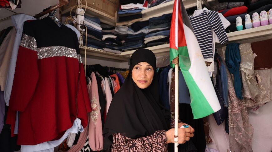 A shop owner carries a Palestinian flag in her store in the Shatila refugee camp in Beirut