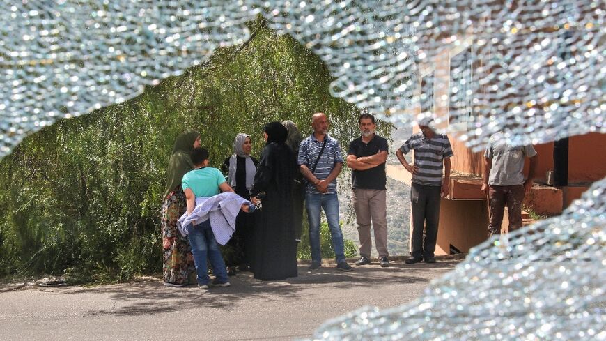 Onlookers are seen through the smashed windshield of the school bus that was damaged in the strike