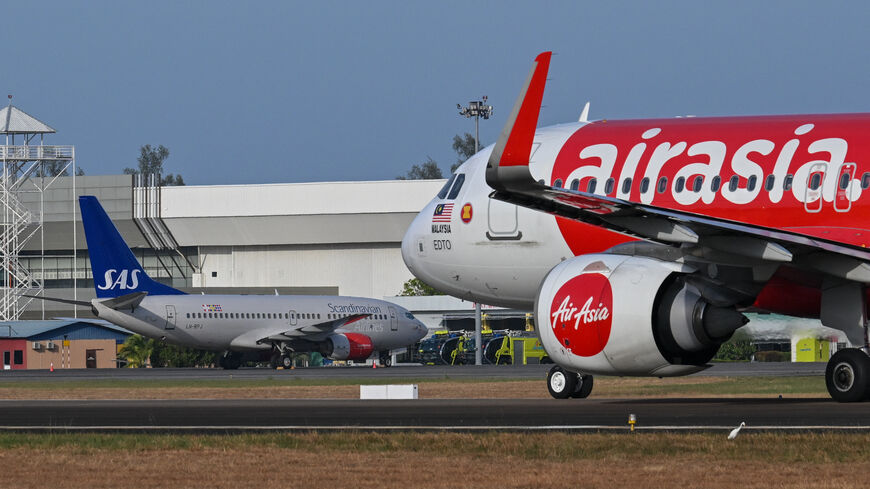 A Scandinavian Airlines (SAS) Boeing 737-700 aircraft (background L) is seen past an AirAsia plane at Langkawi International Airport on the Malaysian resort island of Langkawi on March 2, 2024, ahead of the expected departure of Norway's King Harald V who has been hospitalised on the island. Norway's King Harald V, aged 87 and in poor health, is expected to return in "a few days" from Malaysia where he is hospitalised, the royal household said February 29. (Photo by Mohd RASFAN / AFP) (Photo by MOHD RASFAN/