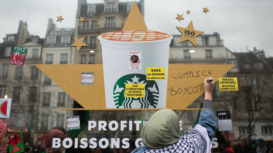 A woman writes "complicit" and "boycott" on a Starbucks window.