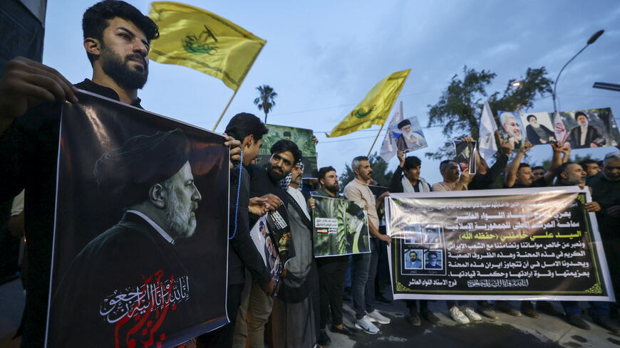 Iraqis carry portraits of Iran's late president Ebrahim Raisi outside the Iranian embassy in Baghdad during a condolences service on May 20, 2024 for the president and his entourage, who were killed in a helicopter crash in Iran the previous day.