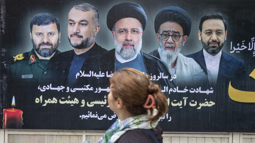 An Iranian woman in Tehran passes by a poster of Iran's late president Ebrahim Raisi two days after his death on May 21, 2024.