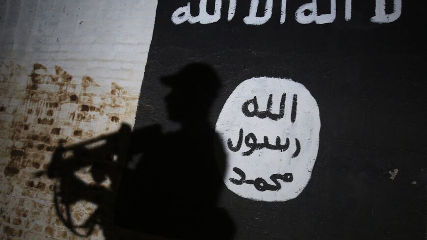 A member of the Iraqi forces walks past a mural bearing the logo of the Islamic State (IS) group in a tunnel that was reportedly used as a training centre by the jihadists, on March 1, 2017, in the village of Albu Sayf, on the southern outskirts of Mosul. 