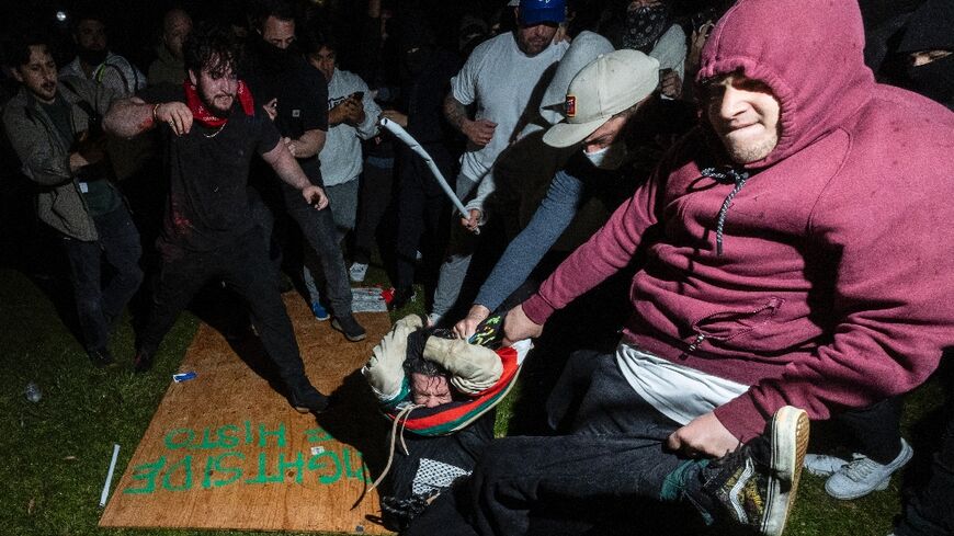 A pro-Palestinian demonstrator (C) is beaten by counter protesters at a pro-Palestinian encampment set up on the UCLA campus in Los Angeles 