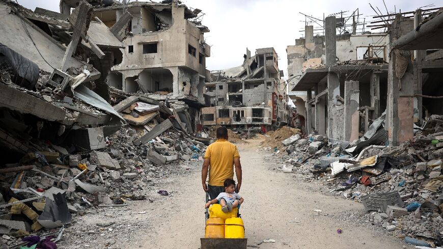 A Palestinian pulls a cart past destroyed buildings in Khan Yunis in southern Gaza